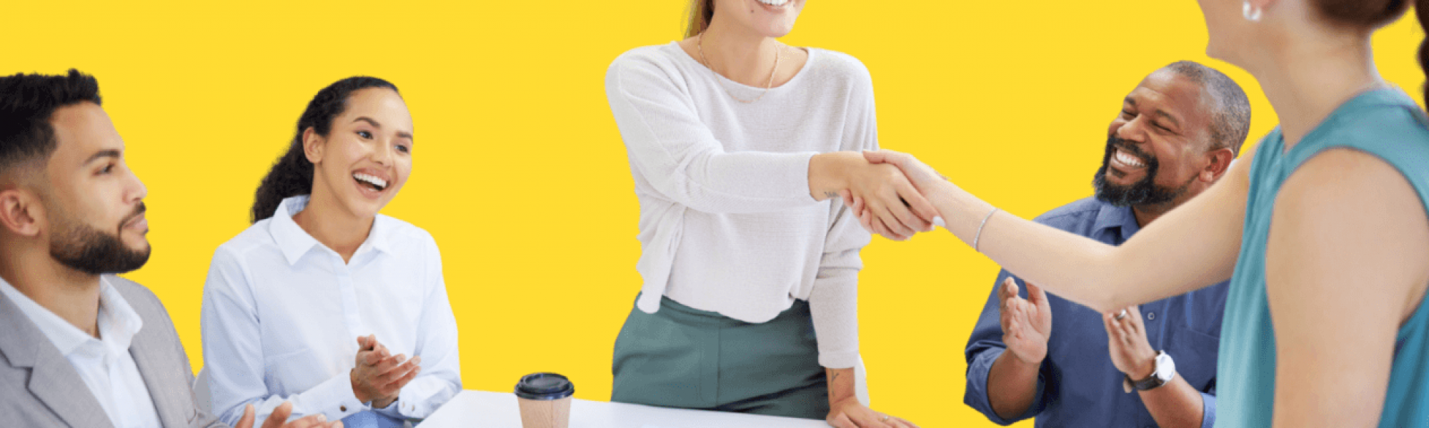 Two women shaking hands at a conference room table.